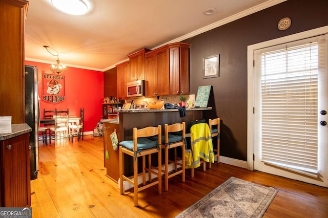 dining space with baseboards, ornamental molding, light wood-type flooring, and a notable chandelier