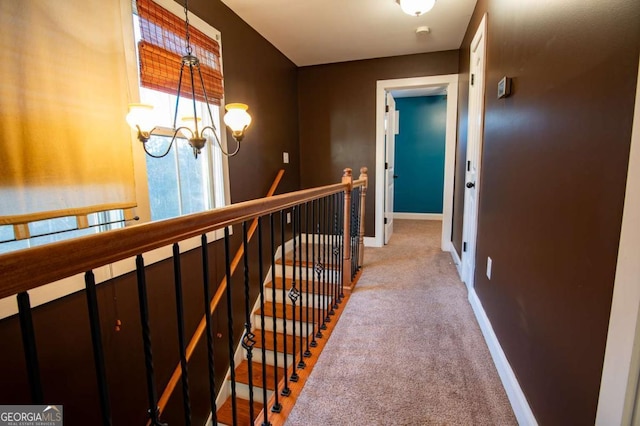 hall with baseboards, a chandelier, an upstairs landing, and light colored carpet