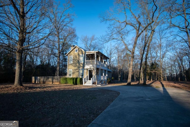 view of front facade featuring a balcony, fence, and concrete driveway