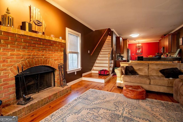 living room featuring baseboards, stairs, crown molding, light wood-type flooring, and a brick fireplace