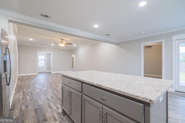 kitchen with visible vents, a kitchen island, open floor plan, wood finished floors, and stainless steel refrigerator with ice dispenser