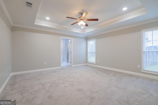 unfurnished room with ornamental molding, a tray ceiling, visible vents, and baseboards