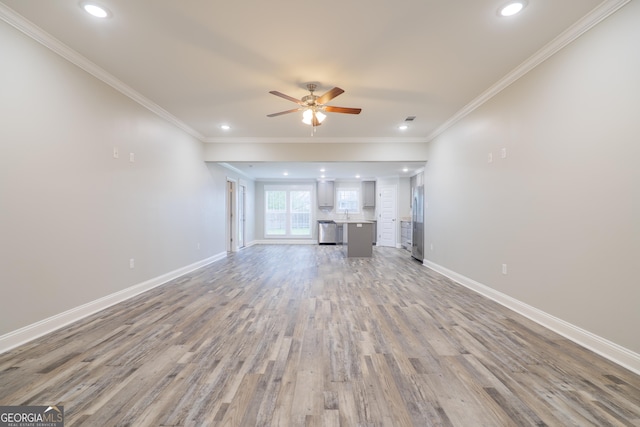 unfurnished living room featuring ornamental molding, a ceiling fan, baseboards, and wood finished floors