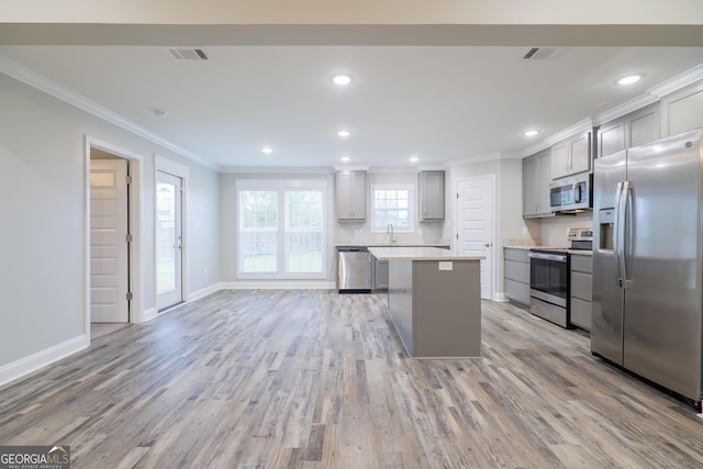 kitchen with appliances with stainless steel finishes, gray cabinets, visible vents, and a center island