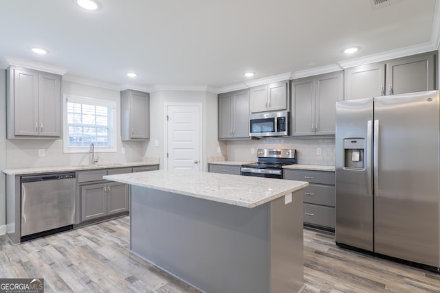 kitchen with crown molding, stainless steel appliances, a kitchen island, and gray cabinetry