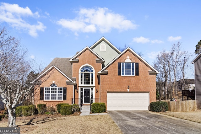 traditional-style home with a garage, brick siding, driveway, and fence