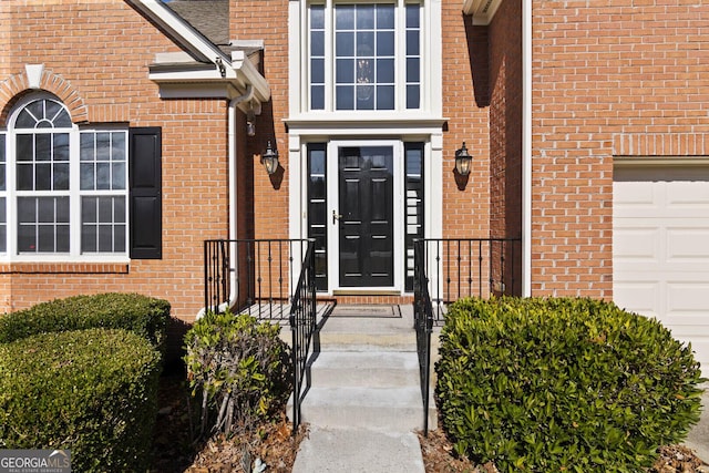 view of exterior entry with brick siding and an attached garage