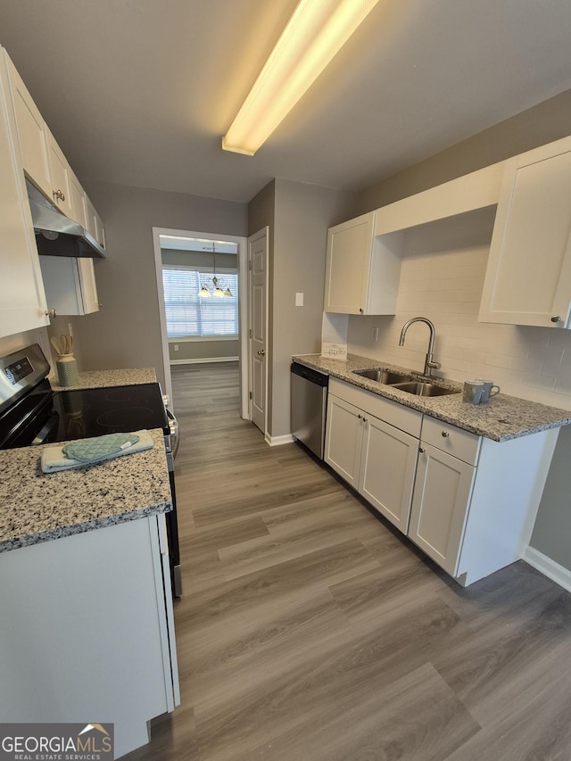 kitchen with light stone counters, a sink, white cabinetry, light wood-style floors, and appliances with stainless steel finishes