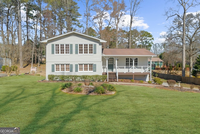 back of property with covered porch, a yard, and fence