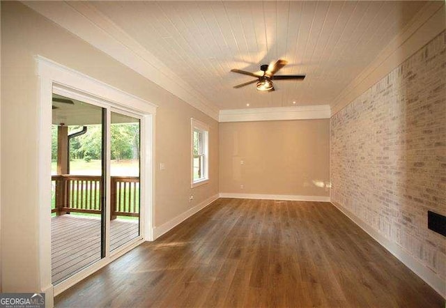 empty room with crown molding, brick wall, dark wood-type flooring, and baseboards