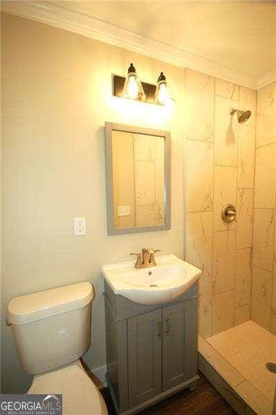 full bath featuring ornamental molding, a shower stall, toilet, and vanity