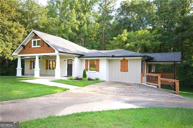 view of front of house with covered porch, driveway, a front lawn, and board and batten siding