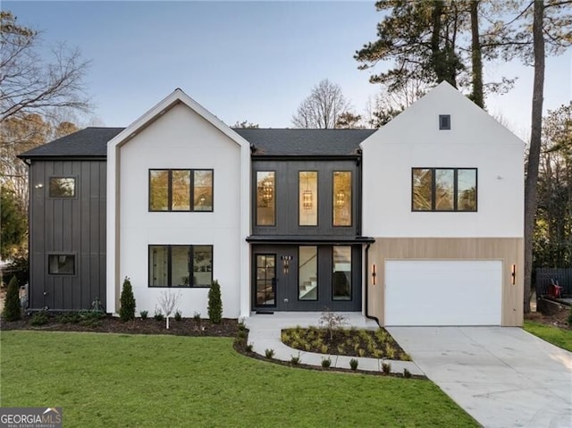 modern farmhouse style home featuring board and batten siding, a front yard, concrete driveway, and an attached garage