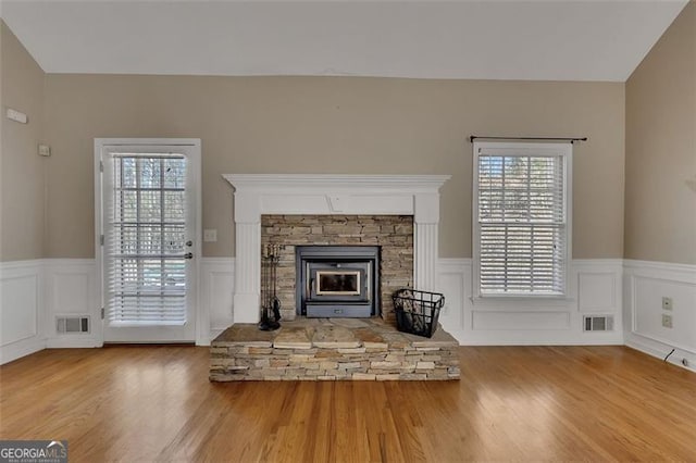 unfurnished living room featuring a wealth of natural light, wood finished floors, and visible vents