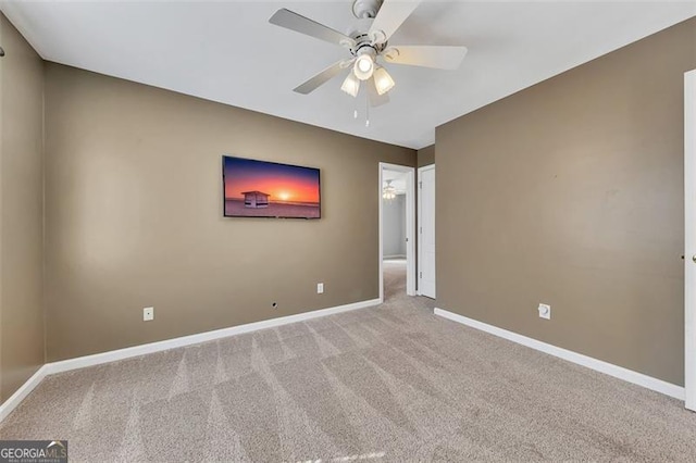 carpeted empty room featuring ceiling fan and baseboards