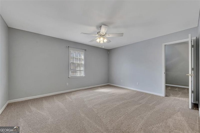 spare room with a ceiling fan, light carpet, and baseboards