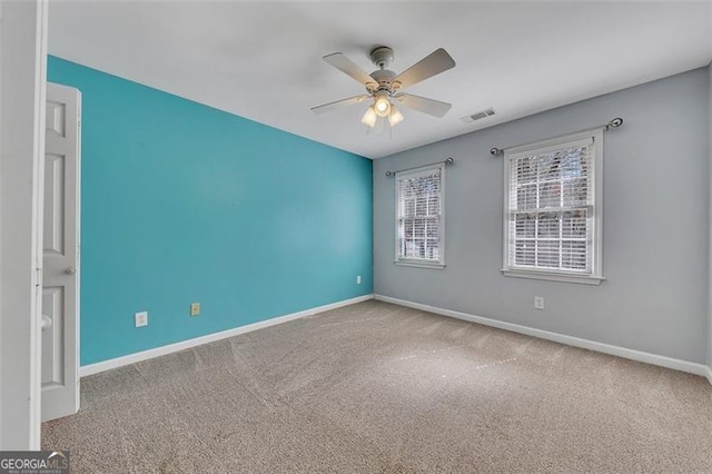 carpeted empty room featuring visible vents, ceiling fan, and baseboards