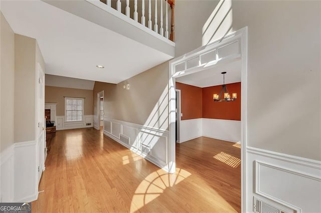 interior space featuring visible vents, wainscoting, wood finished floors, a fireplace, and a chandelier