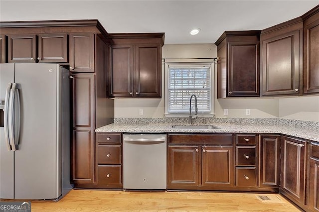 kitchen featuring appliances with stainless steel finishes, a sink, and dark brown cabinetry