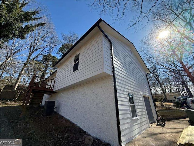 view of property exterior featuring a garage, stairway, cooling unit, and stucco siding