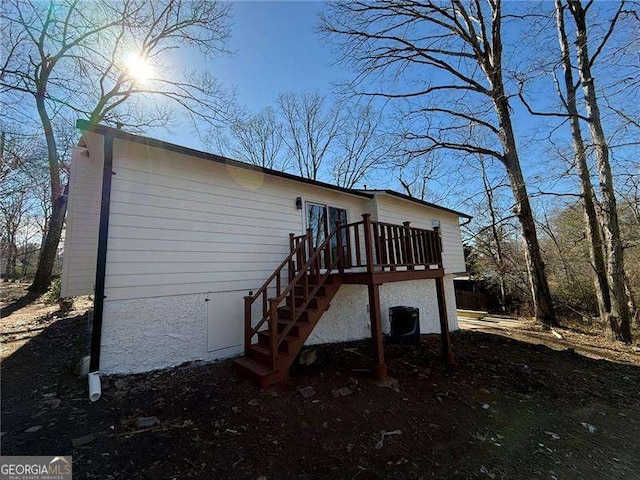 view of home's exterior with stairway, a wooden deck, and central air condition unit