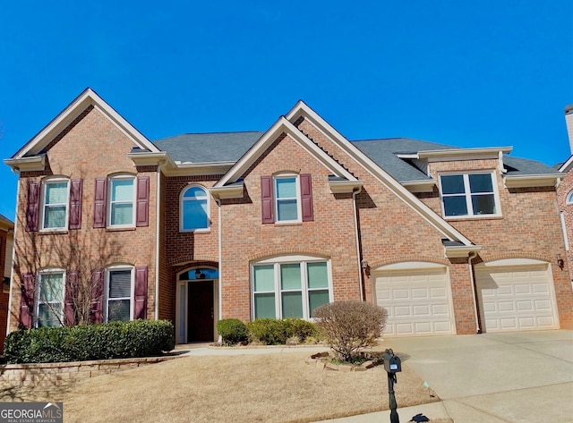 multi unit property featuring a garage, driveway, and brick siding