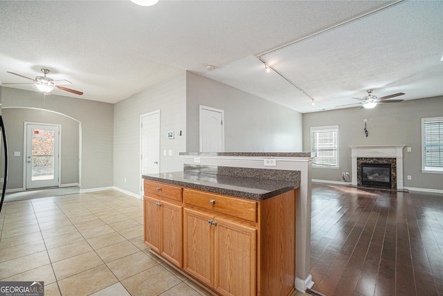 kitchen featuring a textured ceiling, a premium fireplace, a ceiling fan, and a center island