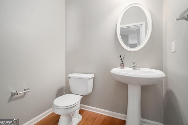 bathroom with toilet, baseboards, and wood finished floors