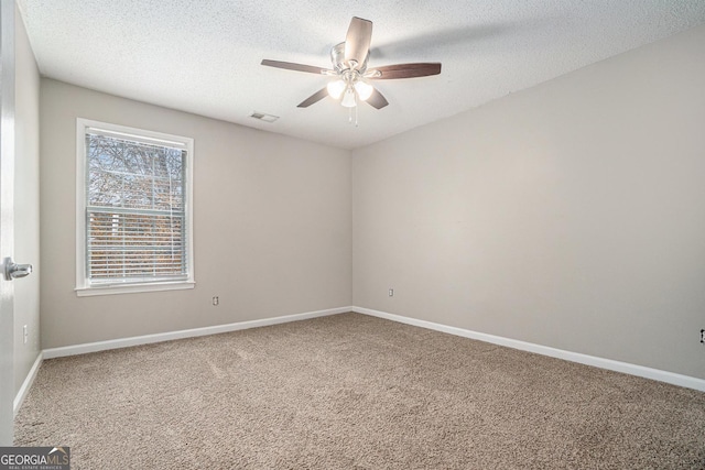 carpeted spare room featuring visible vents, ceiling fan, a textured ceiling, and baseboards