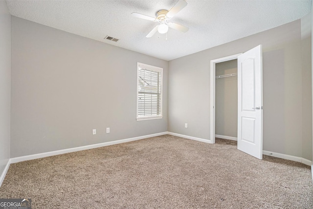 unfurnished bedroom featuring carpet, visible vents, a textured ceiling, and baseboards