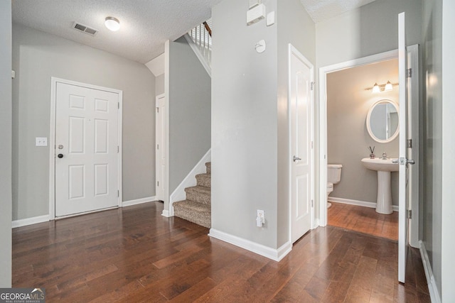 entryway featuring visible vents, stairway, a textured ceiling, baseboards, and hardwood / wood-style flooring