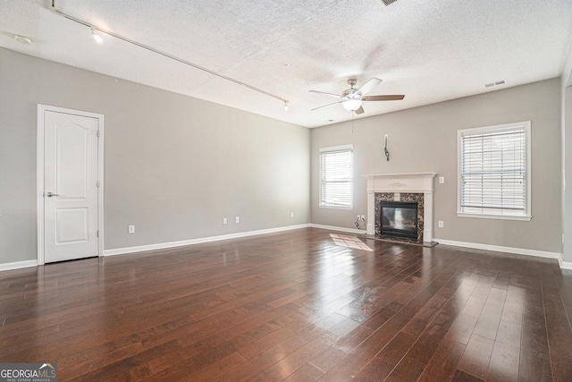 unfurnished living room with hardwood / wood-style flooring, ceiling fan, a fireplace, and a textured ceiling