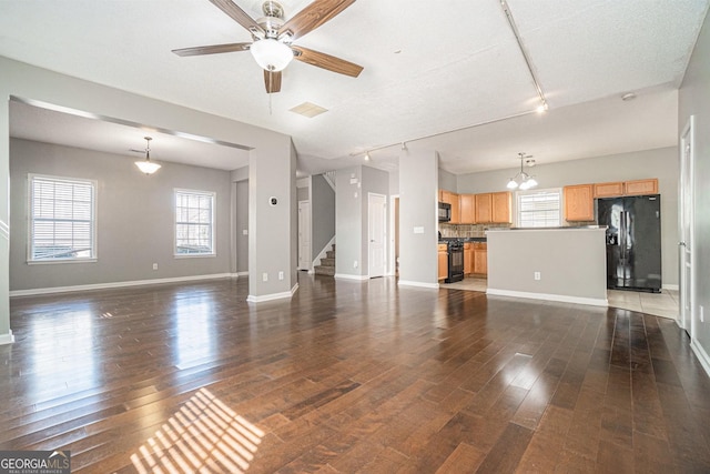 unfurnished living room featuring visible vents, wood finished floors, a wealth of natural light, and baseboards