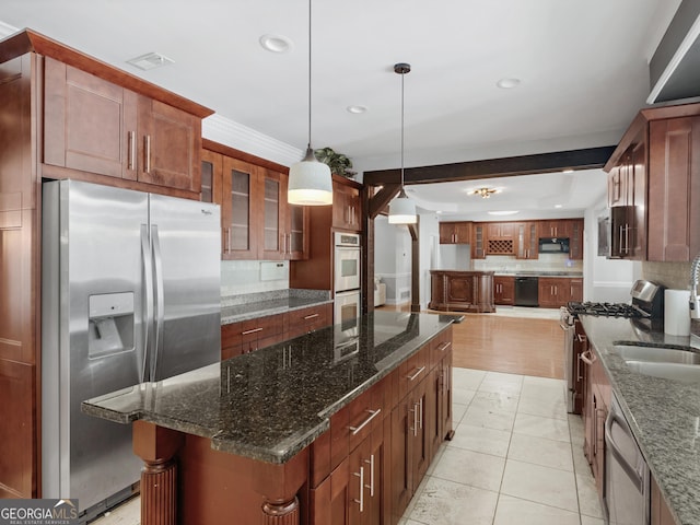 kitchen featuring hanging light fixtures, a center island, black appliances, dark stone countertops, and glass insert cabinets