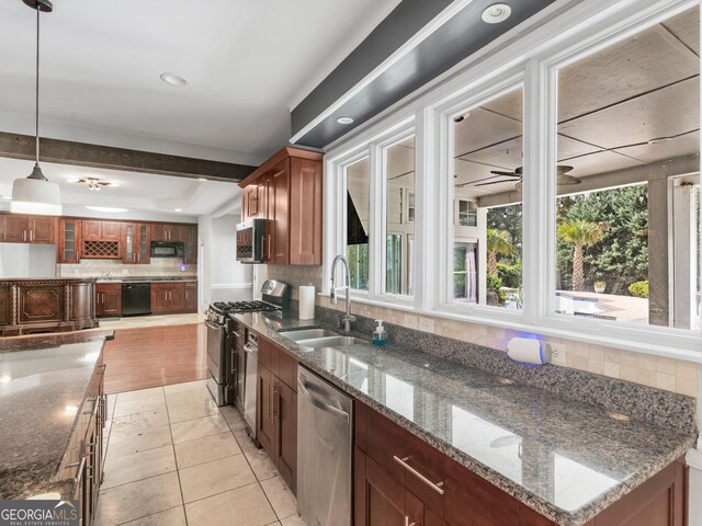 kitchen featuring hanging light fixtures, backsplash, a sink, dark stone countertops, and black appliances