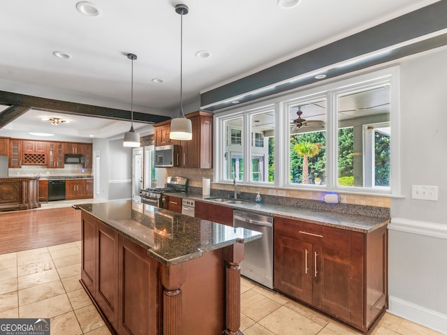 kitchen with dark stone countertops, a center island, black appliances, pendant lighting, and a sink