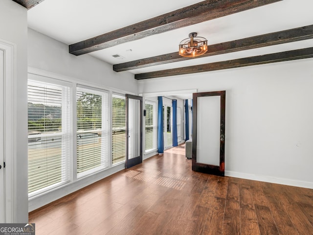 unfurnished room with visible vents, baseboards, dark wood-type flooring, and beamed ceiling