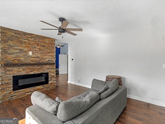 living area with dark wood-style floors, ceiling fan, baseboards, and a glass covered fireplace