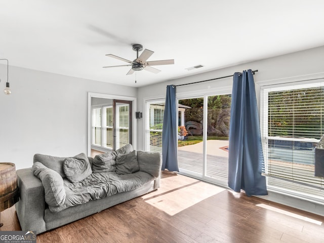 living area featuring a ceiling fan, visible vents, and wood finished floors