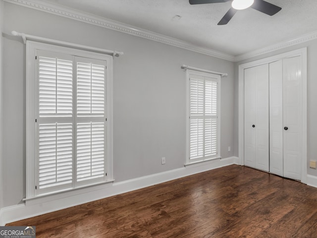 unfurnished bedroom with baseboards, ceiling fan, dark wood-style flooring, crown molding, and a closet