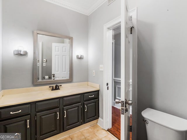 half bath with crown molding, vanity, toilet, and tile patterned floors