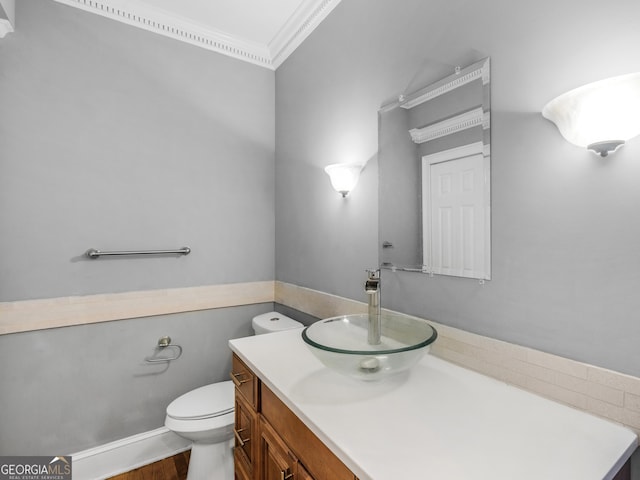 bathroom with toilet, ornamental molding, and vanity