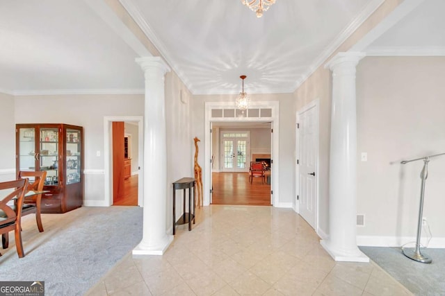 entrance foyer with a chandelier, crown molding, and ornate columns