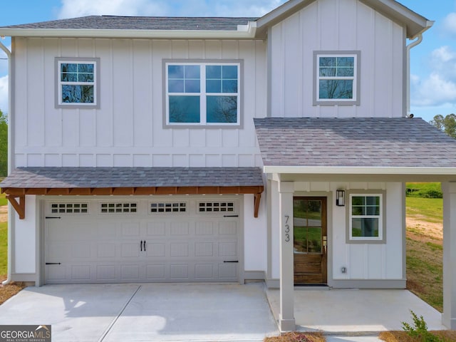 view of front facade with an attached garage, concrete driveway, board and batten siding, and roof with shingles