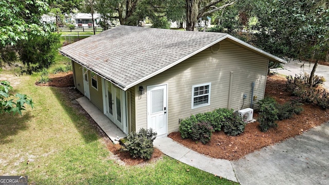 view of home's exterior with a yard, a shingled roof, and ac unit