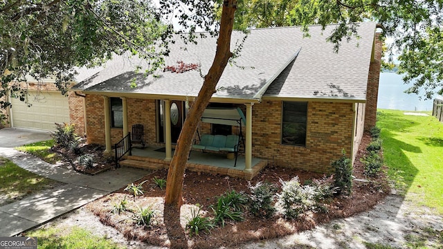 view of front of house with a shingled roof, brick siding, a porch, and a garage