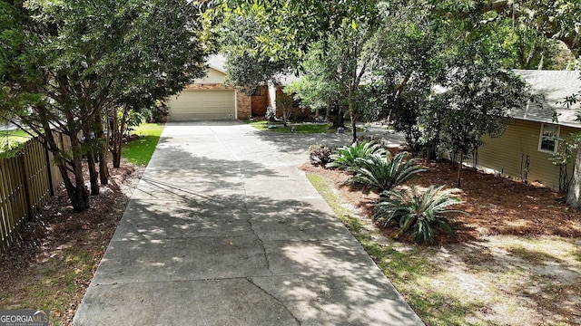 exterior space featuring a shingled roof, fence, concrete driveway, and brick siding