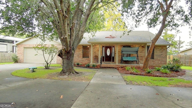 ranch-style house featuring brick siding, fence, driveway, and an attached garage