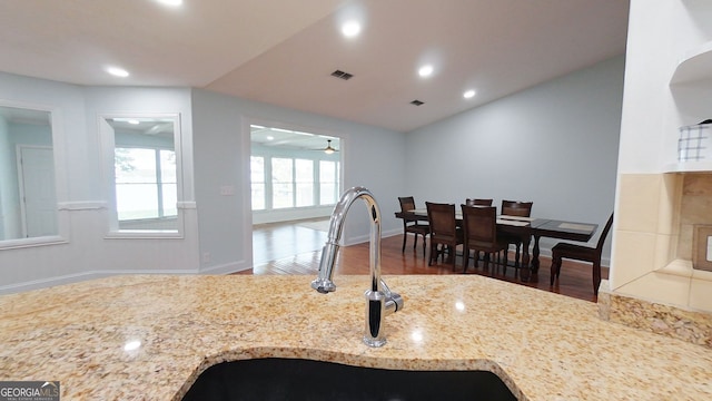 kitchen with light stone counters, visible vents, a sink, and wood finished floors