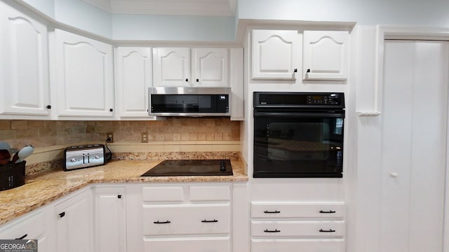 kitchen with black appliances, light stone counters, white cabinets, and backsplash